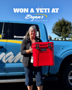 2026 Bryan's Yeti Giveaway winner Christine Lenselink holding the Yeti Roadie 24 cooler standing in front of a blue Bryan's pick up truck